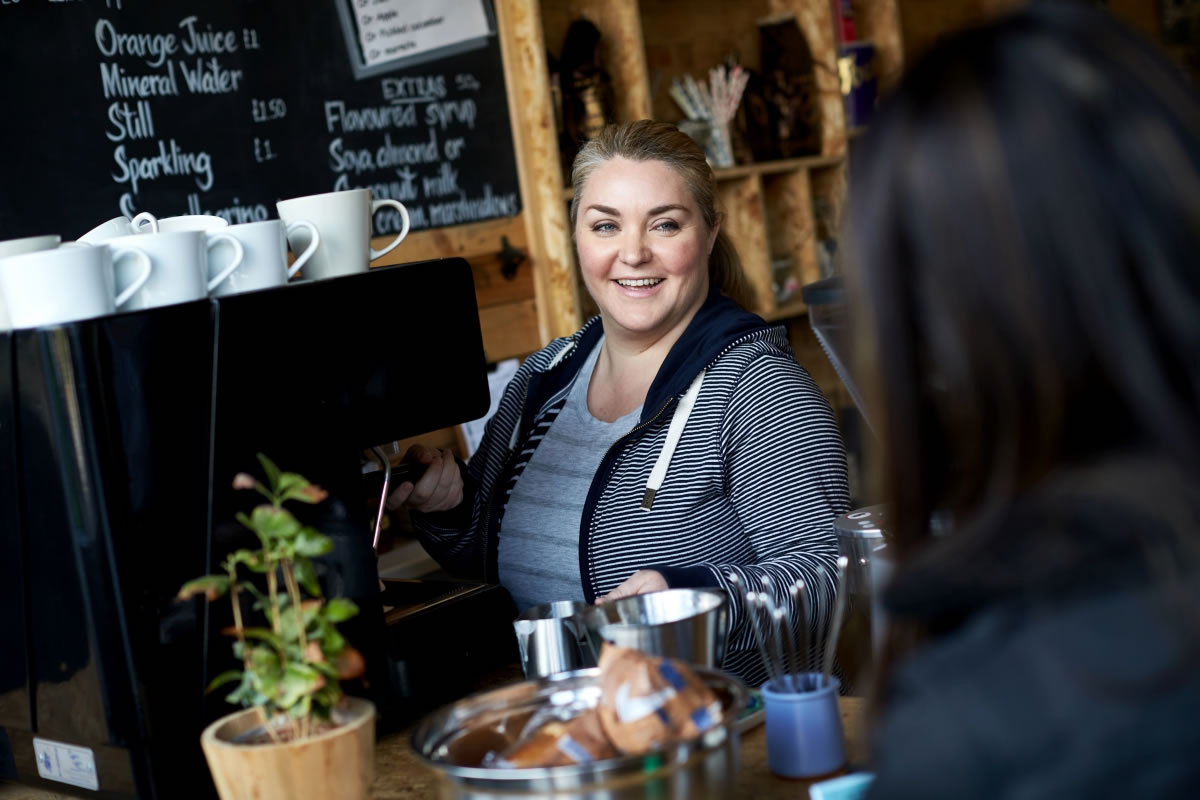 A female barista serves a customer a coffee