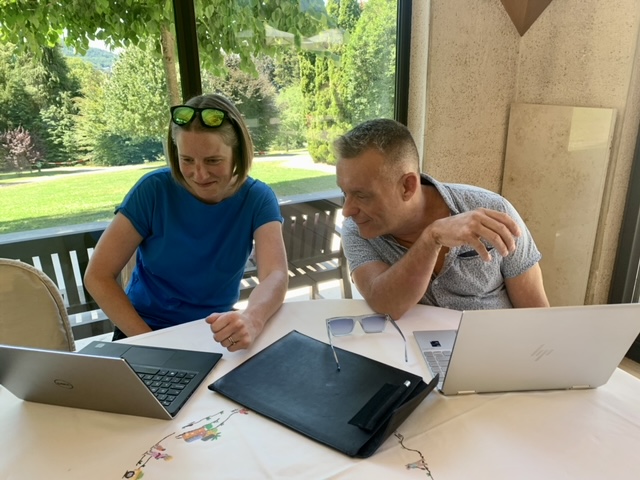 Two attendees working on laptops, one leans in to view what is on the other's screen