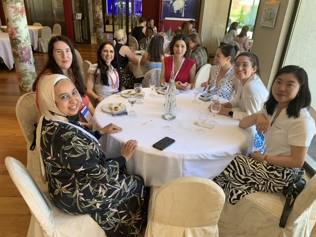 seven attendees sit around a table and smile for a photograph