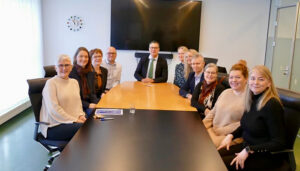 Group of professionals seated around a conference table, smiling at the camera.