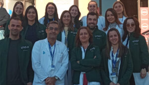 A group of medical staff in uniforms posing for a photo outside of a hospital.