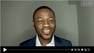 A man in a suit and shirt speaks in front of a plain background. The screen shows video player controls and the EASO logo in the top right corner.