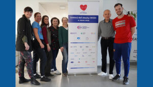 Seven people standing beside a banner with logos, promoting World Obesity Day, March 4, 2024. They are smiling and posing for the photo in an indoor setting.